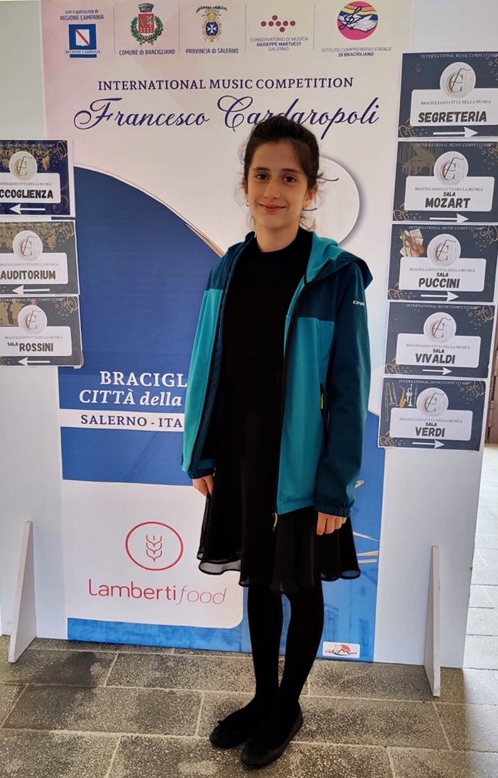 Die Wettbewerbsgewinnerin Mathilde Botti Marques zu sehen vor einem Banner mit der Aufschrift Internatinal Music Competition „Francesco Cardaropoli“ in Bracigliano (Italien)