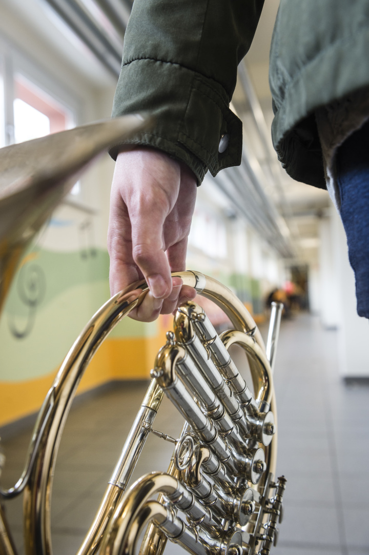 Person läuft mit Horn in der Hand im Kellergang der Musik- und Kunstschule Jena