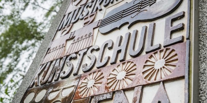Steinschild am Eingang der MKS mit Illustrationen und Aufschrift Musik- und Kunstschule Jena