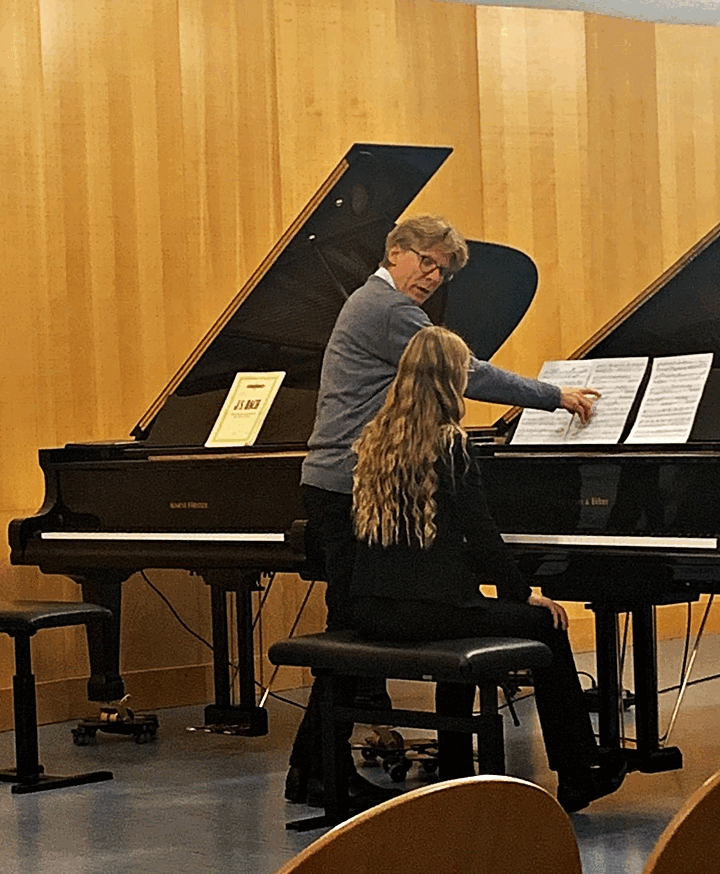 2 Flügel stehen im raum, an einem sitzt eine Schülerin, die etwas von einem Dozenten erklärt bekommt