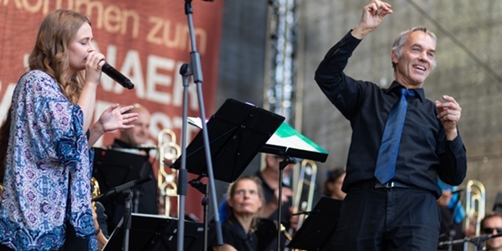 Big Band auf der Bühne Altstadtfest_Dirigent schaut in die Kamera und Sängerin am Mikro, Big Band im Hintergrund  &copy;Tina Peißker