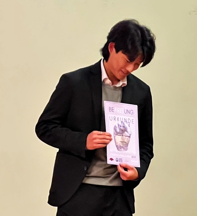 Valentin Wu hält eine Urkunde in der Hand